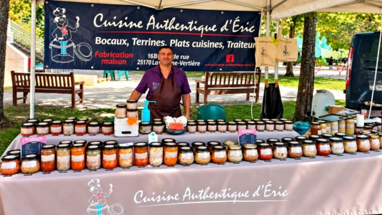 Éric derrière son stand Cuisine Authentique d’Éric, garni de bocaux et de terrines sur un marché