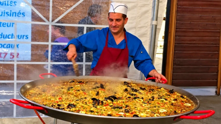 Éric prépare une grande paella dans une poêle lors d’un événement