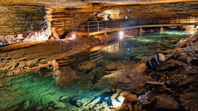 Rivière souterraine aux eaux limpides et passerelle aménagée dans les Grottes de Bèze