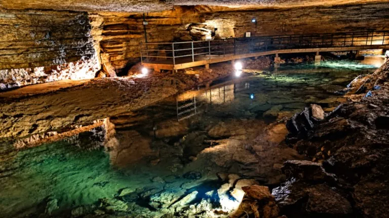 Rivière souterraine aux eaux limpides et passerelle aménagée dans les Grottes de Bèze