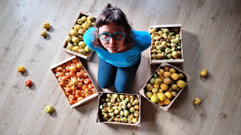 Nina entourée de cagettes de fruits destinés aux préparations de La Petite Glaneuse.