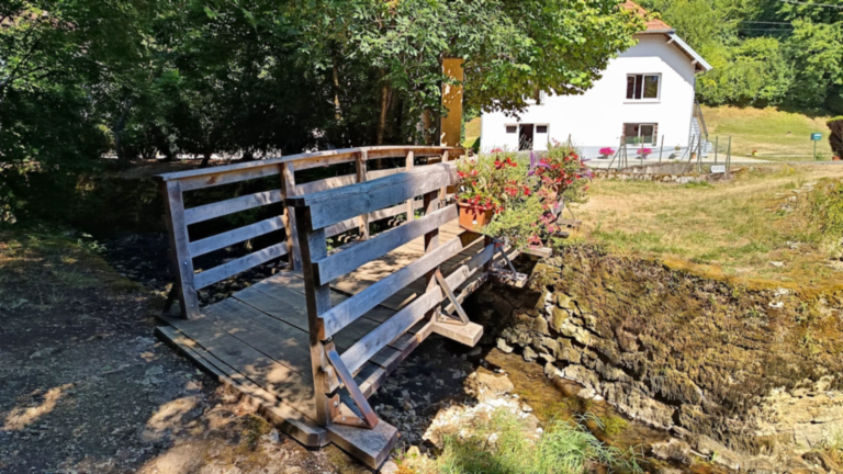 Petit pont en bois fleuri franchissant un cours d’eau au Val de Cusance