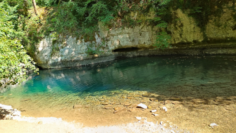 Eaux turquoise de la Source Bleue de Cusance au pied d’une paroi calcaire dans la vallée du Cusancin