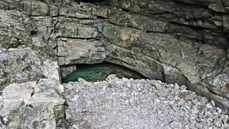 Eaux turquoise de la Source Bleue de Cusance au pied d’une paroi calcaire dans la vallée du Cusancin