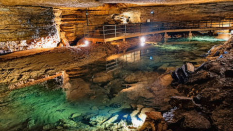 Rivière souterraine aux eaux limpides et passerelle aménagée dans les Grottes de Bèze